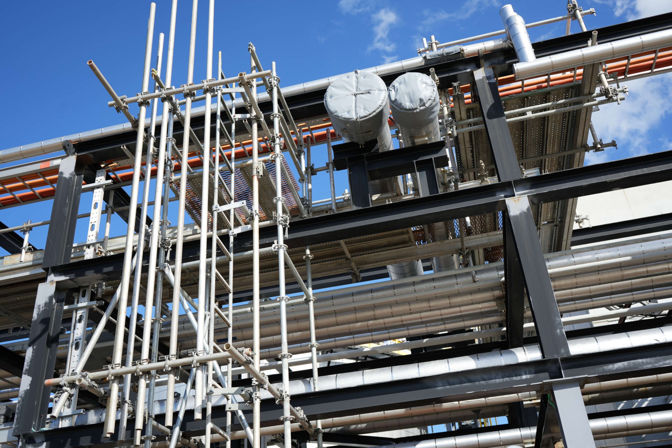 Looking up at Indigenous scaffolding in Alberta with a bright blue sky behind the scaffolding.